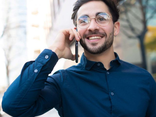 portrait-young-man-talking-phone-while-walking-outdoors-street-urban-concept-scaled